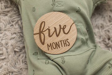 five months old milestone sign wooden of a baby boy in a green outfit