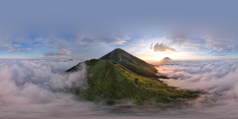 Fototapeta premium Aerial view of Mount Sindoro and Kembang, two iconic Indonesian volcanoes, shrouded in mist at sunrise. A stunning natural landscape.