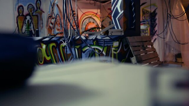 Empty messy criminals base of operations with graffiti drawings sprayed on walls. Electric cables hanging in derelict ghetto hideout used by vandals to commit illegal activities.