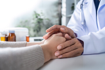 Compassionate Female Doctor Comforting Patient by Holding Hands in a Medical Setting