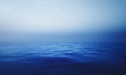 Obraz premium A serene, blue seascape with calm waters blending into a soft, hazy horizon, evoking a sense of tranquility and vastness.