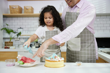 child daughter and father making a cake in the kitchen