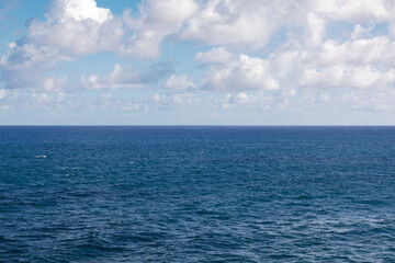 Obraz premium Seascape with blue sea and white clouds on blue sky.