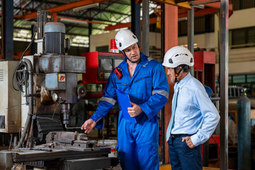 young caucasian technician in safety gear holding paper document is explaining a welding machine maintenance  to experienced supervisor at robot factory