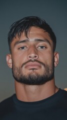 Obraz premium Confident Young Man with Intense Gaze Against a Dusk Background