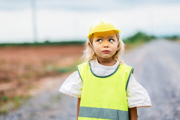 young girl wearing a yellow vest stands on a road
