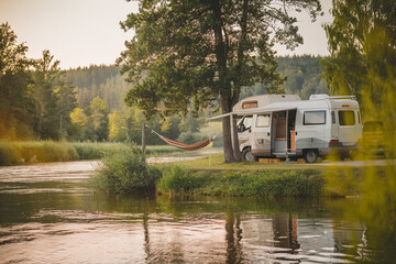 Camper van parked by a river with a hammock strung between trees