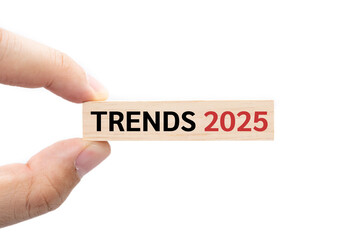 Text TRENDS 2025 wooden block on hand with Clipping path isolated on white background. marketing monitor, business planning.