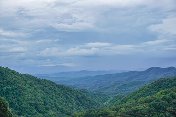 Obraz premium A beautiful landscape of the complex mountains range rolling over endlessly in a cloudy sky in Chiang Mai, Thailand. A symbol of relaxation holidays in winter up in the hill