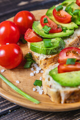 Avocado toast topped with tomato and green onion on a slice of carrot bread