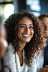 A smiling woman with curly hair, wearing a white sweater, looking at the camera