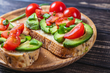 Avocado toast topped with tomato and green onion on a slice of carrot bread