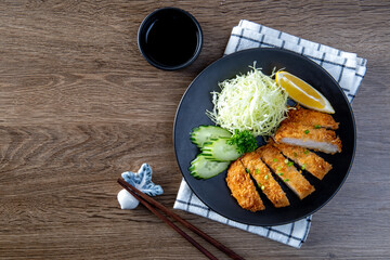 Japanese pork cutlet and shredded cabbage on a black plate