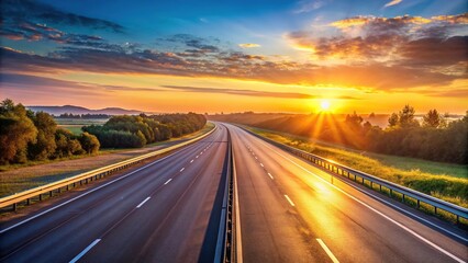 Naklejka premium Highway at sunrise with golden hour light illuminating landscape