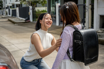 Asian mother saying goodbye to her little daughter as she drops her off at school in the morning.