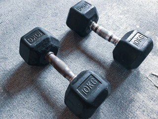 Various black dumbbells rest in a modern gym, ready for use. The empty space highlights a commitment to fitness and strength training.