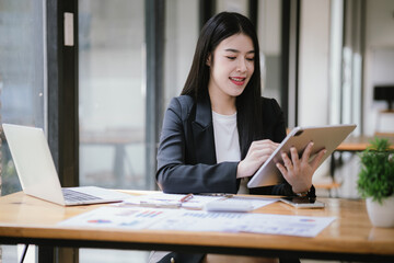 Freelance Asian businessman working independently using tablet computer in modern office. Accounting analysis report, real estate investment information, financial and tax concept.