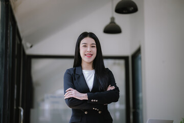 Professional Asian businesswoman using mobile phone and laptop in office