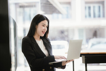 Fototapeta premium Beautiful Asian businesswoman talking on the phone using laptop in office