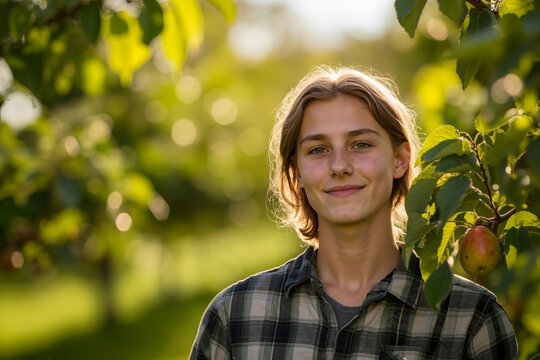 A young woman with long blonde hair is smiling and standing in a sunlit orchard, surrounded by apple trees