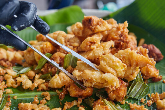 Close-up of hand picking up deep-fried chempedak seed