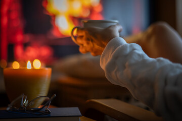 Cup Of Coffee In Woman's Hands Sitting Near Fireplace