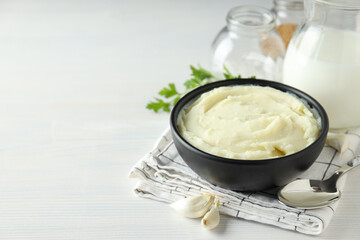 Mashed potatoes in bowl on towel, spoon and spices on white background, space for text