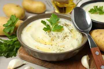 Mashed potatoes in bowls, spoon and ingredients on gray background, close up