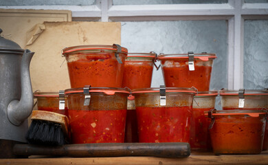 Fototapeta premium A row of glass jars filled with red sauce sit on a wooden table