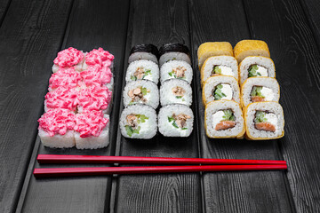 Mix, assorted Japanese sushi, rolls on a black wooden background.