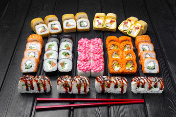 Mix, assorted Japanese sushi, rolls on a black wooden background.