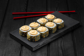 Japanese sushi, rolls fried with cheese sauce on top on black wooden background. Tempura roll