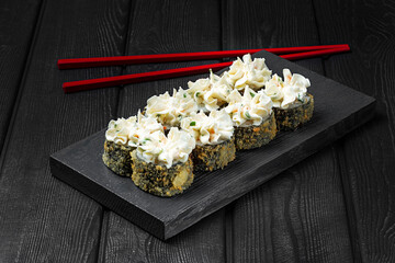Japanese sushi, rolls fried with cheese sauce on top on black wooden background. Tempura roll