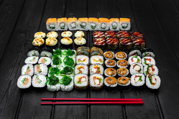 Mix, assorted Japanese sushi, rolls on a black wooden background.
