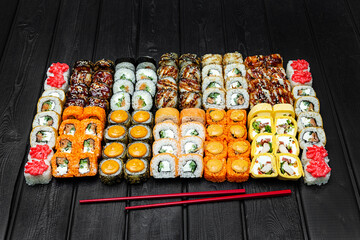 Mix, assorted Japanese sushi, rolls on a black wooden background.