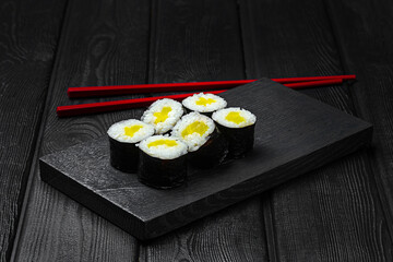 Japanese maki sushi with bell pepper on black wooden background.