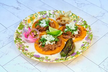 Mexican beef tacos with jalapenos, parsley, and fresh lime on ceramic surface