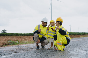 Engineer family in survey set father mother and son inspect and work on wind farm rotating to electricity renewable energy alternative for clean energy concept