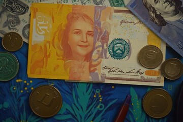 A collection of various currencies, including bills and coins, arranged on a colorful surface.