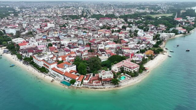 Aerial video footage of area around the historic Stone Town, the oldest part of Zanzibar Town on Unjuja island, Tanzania, starting at Shangani Beach, flying across historic buildings and landmarks