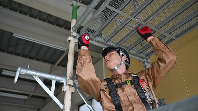 足場などを組み立て建設現場で働く作業員　クローズアップ　真剣な表情で働くガテン系作業員動画