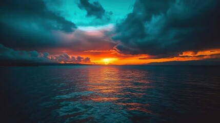 Fototapeta premium A vibrant sunset over the ocean, with dramatic clouds casting long shadows on the water.