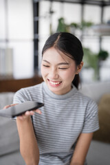 Asian woman using voice assistant on smartphone at home conversation with online assistant Voice...