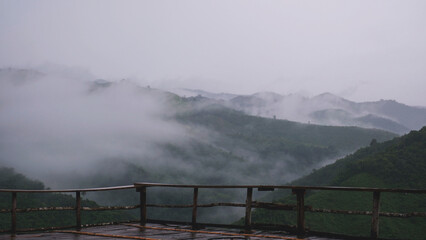 Naklejka premium Landscape of greenery rainforest and hills outside wooden terrace on foggy day