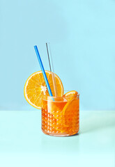 Aperol Spritz cocktail with orange slice. Bright orange drink on blue backdrop. Copy space
