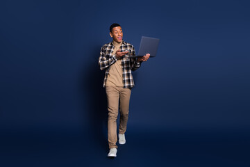 Full length photo of funky cool guy dressed plaid shirt video call modern device emtpy space isolated blue color background