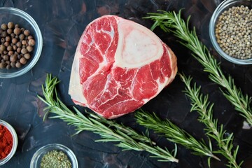 Raw meat lies on a dark background surrounded by spices. Meat production.