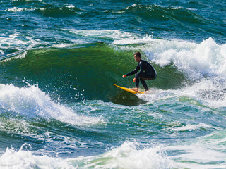 Male surfer surging on surfboard at middle of sea on sunny day