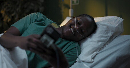 Patient with oxygen tube in hospital uses phone in hospital ward.