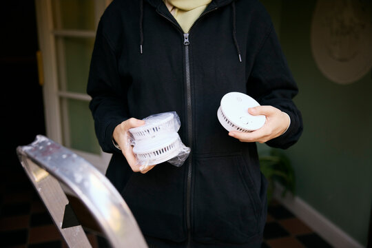 Midsection of woman holding smoke detector